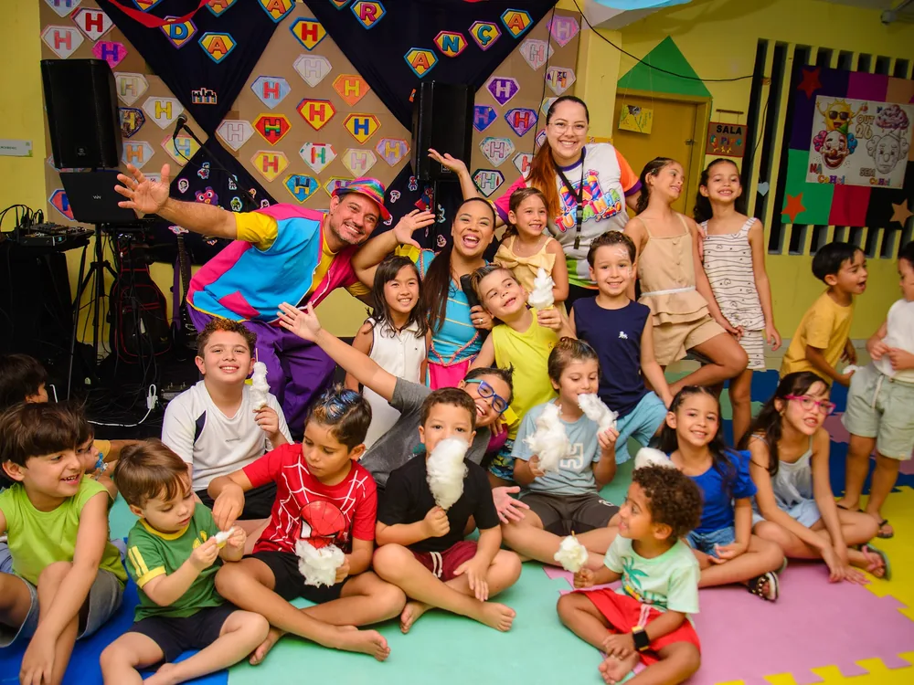 Turma sentada no tatame junto com os educadores, todos sorrindo